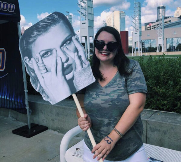Maggie Kooi holds up a Taylor Swift Poster