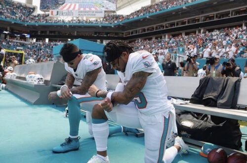 Two members of the Miami Dolphins kneeling during an NFL game