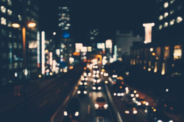 Dark City Lights with Cars on the interstate. Tall buildings surrounding the interstate.