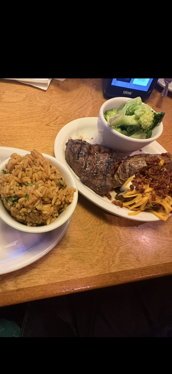 A photo of food. Steak, rice, sweet potato, and broccoli on white plates